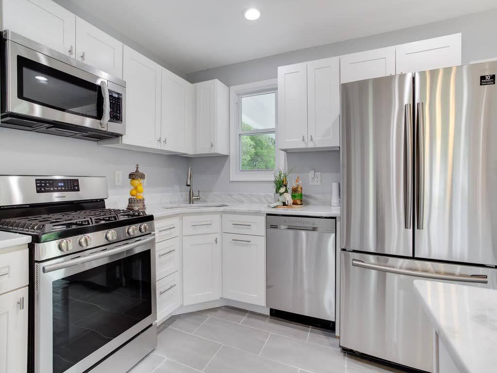 Kitchen after renovation with white shaker cabinets and stainless appliances