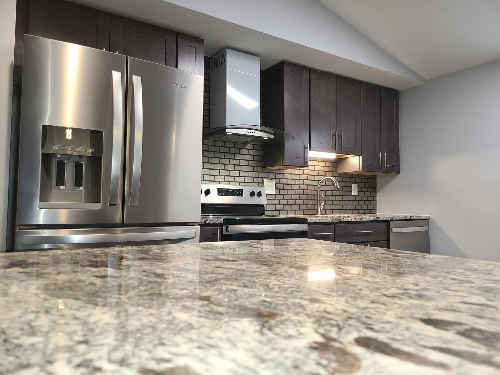 Renovated kitchen island with granite counters and stainless appliances